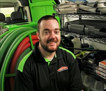 Smiling male employee with dark hair and beard.