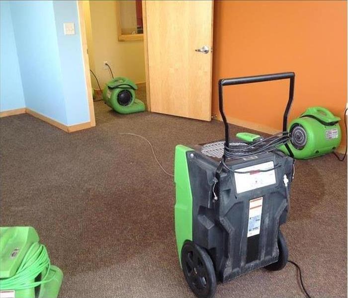 Drying equipment, air movers and dehumidifiers drying a wet carpet.